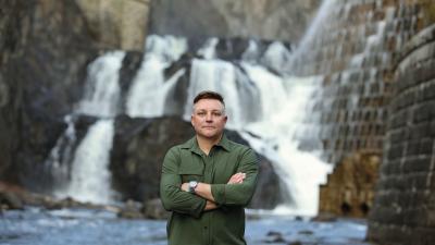 Seth Schultz seen posing in front of a waterfall.
